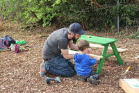 Ein Mann und ein kleiner Junge bauen eine Sitzgarnitur für Kinder auf.