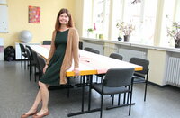 Nicole Novak lehnt an dem großen Gruppentisch im Saal der Stiftung Soziale Gemeinschaft Riedstadt