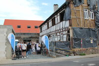 Viele Menschen stehen auf dem Hof des Wohnprojektes "Storchennest" mit alten Gebäuden