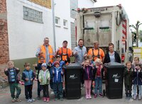 Kinder der Kita Sonnenschein stehen mit Leuten von der Müllabfuhr vor einem Müllauto. Alle strecken den Daumen nach oben.