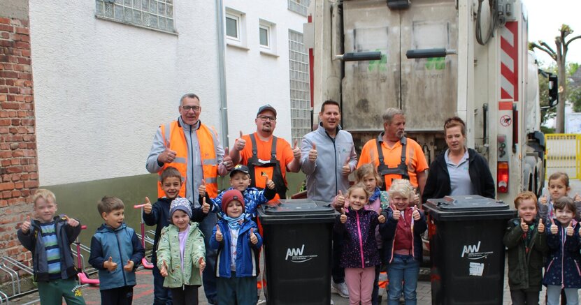 Viel Spaß hatten die Kita-Kinder mit dem Team vom AWV Kinder der Kita Sonnenschein stehen mit Leuten von der Müllabfuhr vor einem Müllauto. Alle strecken den Daumen nach oben.
