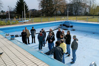 Mitglieder des Sanierungsvereins stehen 2008 im leeren Schwimmerbecken. Mitglieder des Sanierungsvereins stehen auf dem blauen Boden des leeren Schwimmerbeckens. Sie beraten, wie es saniert werden kann.