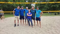 Die Vorjahressieger „Fürst von Schmetternicht“ wollen ihren Titel verteidigen Das Team von "Fürst von Schmetternicht" stehen in blauen T-Shirts auf dem Sand eines Beachvolleyball-Feldes. Im Hintergrund sind die Liegewiese des Freibads Goddelau und Bäume zu sehen.