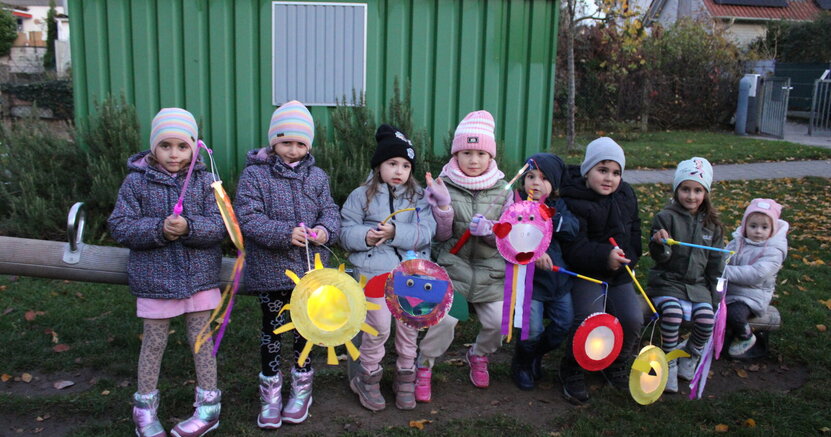 Kinder der Kita Büchnerstraße sitzen mit ihren Laternen auf einer Wippe.