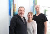 Kai Faßnacht, Julia Spitzer und Heiko Wambold (v.li.) vom Jugendbüro stehen vor einer weißen Wand mit buntem Wandbehang.