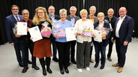 Vor dem dunklen Vorhang auf der Bühne stehen Stadtverordnetenvorsteher Guido Funk und Bürgermeister Marcus Kretschmann links und rechts von Samer Chawaf, Melanie Stahlecker-Zach, Gaston Wolfsturm, Bärbel Fischer, Gerald Kummer, Regina Plettrichs, Sebastian Wispel, Carola Friedrich und Wilfried Büdinger. Diese halten ihre Ehrenbriefe in den Händen.