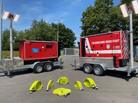 Zu sehen sind Feuerwehrschläuche und Feuerwehrfahrzeuganhänger