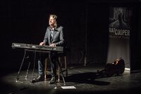 Zu sehen ist Ray Cooper. Er sitzt an einem Keyboard auf der Bühne der BüchnerBühne.