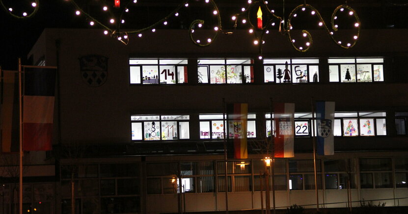 Das hell erleuchtete Rathaus mit geschmückten Adventsfenstern.