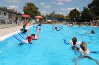 Kinder schwimmen im Freibad Crumstadt mit Hilfe von Nudeln und üben Schwimmbewegungen.