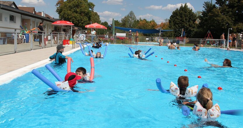 Kinder schwimmen im Freibad Crumstadt mit Hilfe von Nudeln und üben Schwimmbewegungen.