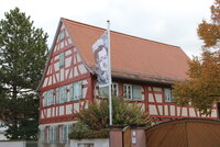 Das Büchnerhaus in der Weidstraße 9. Zu sehen ist das Büchnerhaus von der Straße aus: ein Fachwerkhaus mit roten Balken. Vor dem Haus weht eine Fahne mit dem Bild Georg Büchners.