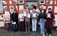 Die Teilnehmerinnen und Teilnehmer des Vorlesewettbewerbs stehen vor dem Büchnerhaus. Mit dabei auch die Juroren Lucia Bornhofen (links), Christian Suhr und Birgit Weinmann. Die Kinder halten Teilnahmeurkunden in den Händen, Lucia Bornhofen ein Plakat mit der Aufschrift "Vorlesewettbewerb".