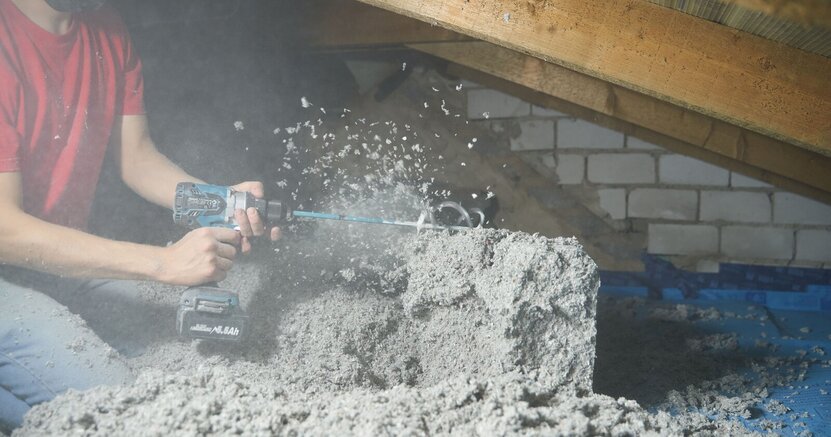 Zu sehen sind Dämmarbeiten auf einem Dachboden. Dabei wird das Dämmmaterial aus Altpapier zerkleinert.