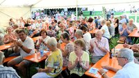 Im voll besetzten Festzelt herrschte beste Stimmung An Biertischen im Festzelt sitzen viele Menschen und klatschen in die Hände.