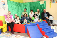 In einem Bällebad mit bunten Bällen sitzen und liegen kleine Kinder. Drumherum sitzen auf der Umrandung Mütter mit ihren Kindern, die Gruppenbetreuer Heike Schuhknecht, Mario Quast und Katharina Jantzen sowie Bürgermeister Marcus Kretschmann.