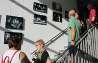 Menschen stehen im Treppenhaus des Riedstädter Rathauses und sehen sich die Fotos an, die dort an der Wand hängen.