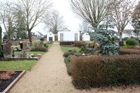 Auf dem Friedhof Goddelau wurde, wie auch in den anderen vier Friedhöfen, die Standfestigkeit der Grabsteine überprüft. In der Mitte des Bildes führt ein Kiesweg zur Trauerhalle auf dem Friedhof in Goddelau. Links und rechts des Weges sind Gräber zu sehen.