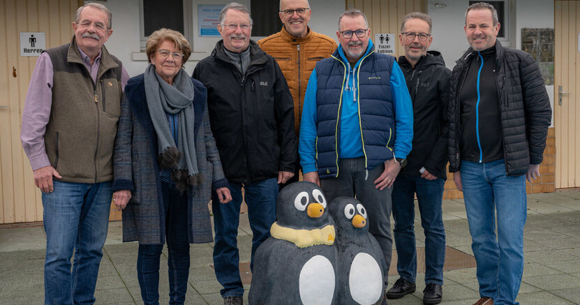 Klaus und Ruth Trapp und Karl-Heinz Kopp (vom Schwimmbadverein) sowie Peter Philipp, Christian Lorenz, Michael Klosterhalfen, Marc Gaillard (vom Linux-Café) stehen am Rand des Schwimmbeckens im Freibad Crumstadt. Vor ihnen stehen zwei Wasserspeier in Form von Pinguinen.