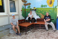 Heiko Wambold, Julia Spitzer und Kai Faßnacht sitzen auf einer Bank vor der bemalten Hauswand des Jugendhauses Goddelau