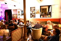 Im gemütlichen Theatercafé findet auch der Club der Dichter statt. Menschen sitzen in alten Sesseln im Theatercafé der BüchnerBühne.