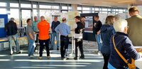 Menschen stehen im Sitzungssaal des Rathauses an Stehtischen und an Infoständen und unterhalten sich.