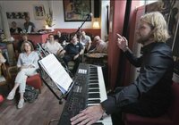 Bastian Hahn am Klavier im Theatercafé, in Hintergrund sind Zuhörer zu sehen.