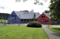 Zu sehen sind ein blaues und ein rotes Haus des Feriendorfs Ober-Seemen, im Vordergrund ist eine grüne Wiese.