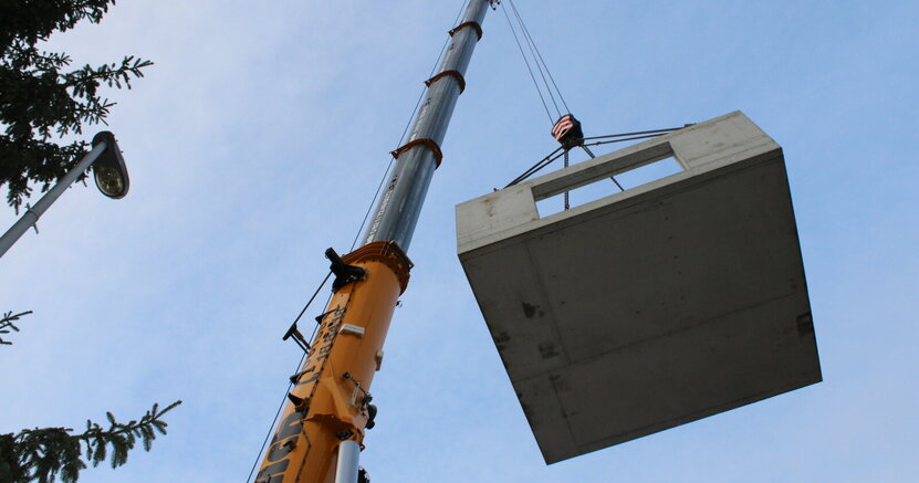 Ein Schwerlastkran hebt das Bauwerk an einem Haken in die Höhe.