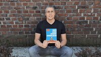 Autor Thomas Reinbacher hält sein Buch in der Hand.