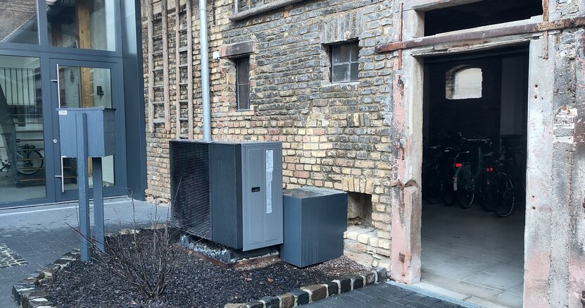 Vor der Außenwand eines Hauses steht eine Wärmepumpe.