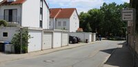 Ein Schild in der Weidstraße weist auf den Ausweichparkplatz hin. Das Foto zeigt die Weidstraße in Goddelau. Im Hintergrund sind die Bäume vor dem Freibad Goddelau zu sehen. Im Vordergrund zeigt vorne rechts ein Schild den Weg zum Ausweichparkplatz für das Freibad Goddelau.