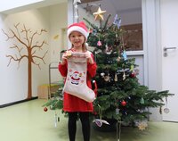 Julia mit Nikolaussäckchen vor dem gespendeten Weihnachtsbaum in der Kita Pfiffikus.