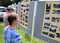 Die Fotoausstellung zur Geschichte des Freibads fand großes Interesse. Eine Frau und ein Mann schauen sich alte Fotos an, die an Stellwänden hängen.