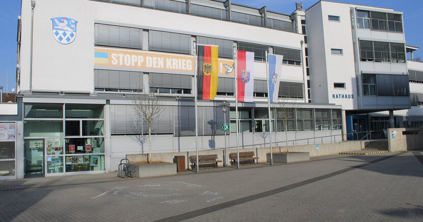 Das Riedstädter Rathaus von außen. Vor dem Gebäude wehen die Deutschlandfahne, die Fahne des Landes Hessen und die der Stadt Riedstadt