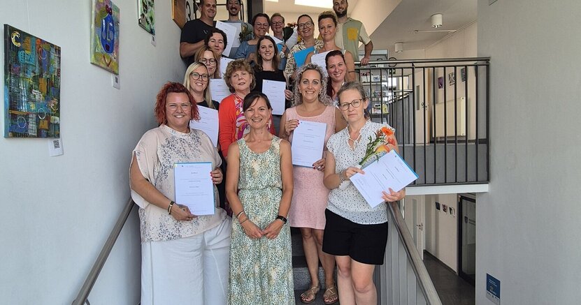 Die erfolgreichen Kita-Führungskräfte mit ihren Zertifikaten. Es gratulierten auch die Pädagogische Fachberaterin Nadja Pfitzner (vorne Mitte) und Fachbereichsleiter Rick Hölzer (hinten rechts) Die erfolgreichen Kita-Führungskräfte stehen mit ihren Zertifikaten auf der Treppe im Riedstädter Rathaus.