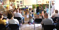 Stimmabgabe bei der ersten Riedstädter Dschungelwahl. Kinder stehen in der Kunstgalerie mit Wahlzetteln vor der Wahlkabine Schlange. Die Wahlkabine besteht aus Sitzkissen, die auf einen Tisch übereinander gestapelt wurden. Ein Kind ist gerade in der Wahlkabine.