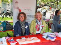 Karina Bonert und Renate Schonemakers (v.li.) vom Verein mamazone sitzen hinter einem Infostand.