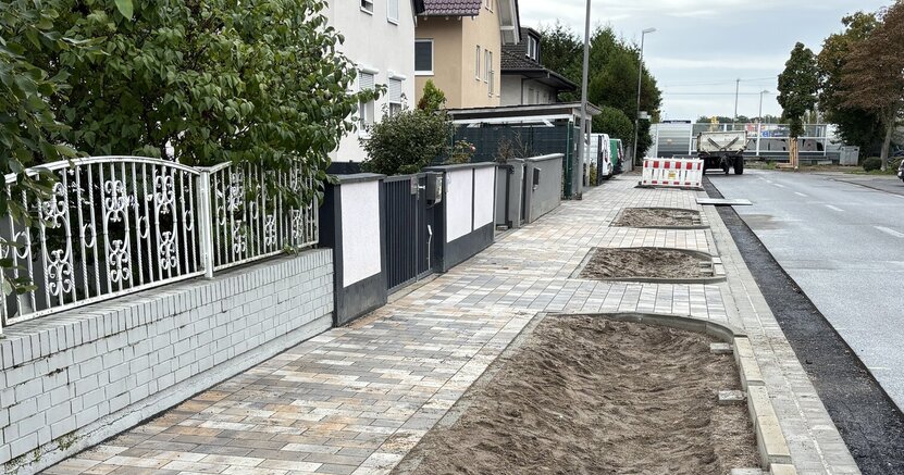 Zu sehen sind der frisch gepflasterte Gehweg, die Pflanzflächen und der neue Asphaltstreifen.