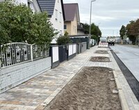 Zu sehen sind der frisch gepflasterte Gehweg, die Pflanzflächen und der neue Asphaltstreifen.