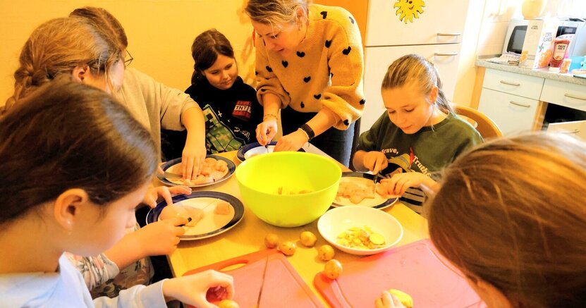 Zu sehen ist ein Bild vom letzten WinterFun. Darauf kocht Jugendpflegerin Julia Spitzer mit Kindern.
