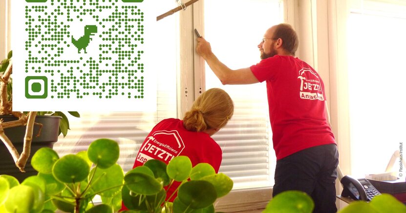 Zu sehen ist ein Mann, der eine Folie an einem Fenster anbringt.