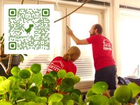 Zu sehen ist ein Mann, der eine Folie an einem Fenster anbringt.