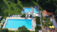Bis einschließlich 9. September wurde die Saison im Freibad Goddelau verlängert. Von oben sind die frei Becken des Freibads Goddelau und die Liegewiesen mit Bäumen zu sehen. Im Vordergrund ist das große Schwimmerbecken mit einem Schwimmer. Dahinter das kleinere Nichtschwimmerbecken und das noch kleinere Planschbecken.