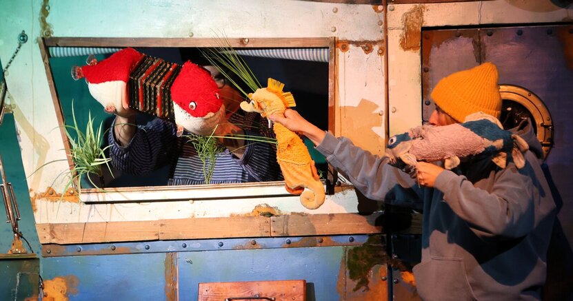Zu sehen sind als Handpuppen ein rot-weißer Fisch, das Seepferdchen Sandy und der Fisch Dommy.