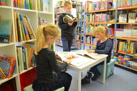 Drei Kinder lesen in der Bücherei Erfelden in Büchern.