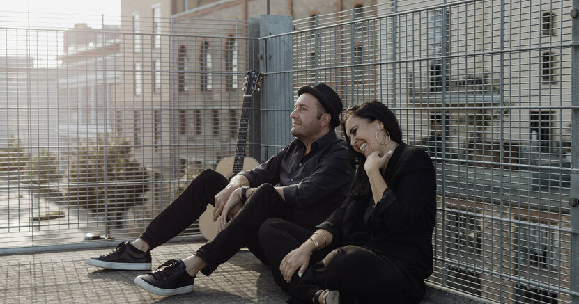 Das Duo Tonland sitzt auf einer Dachterrasse mit Gitterumrandung