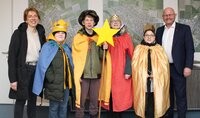 Vier Kinder sind als Sternsinger verkleidet. Eines hat einen Stab mit Stern in der Hand. Neben ihnen stehen ihre Betreuerin Dagmar Bahrenberg und Bürgermeister Marcus Kretschmann.