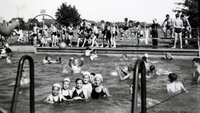 Früher Badespaß im Freibad Crumstadt Auf dem Schwarz-Weiß-Foto sind Badende in einem Beton-Schwimmbecken zu sehen. Die Frauen tragen Badehauben.