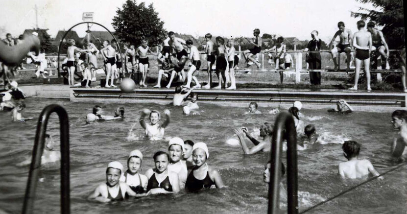 Früher Badespaß im Freibad Crumstadt Auf dem Schwarz-Weiß-Foto sind Badende in einem Beton-Schwimmbecken zu sehen. Die Frauen tragen Badehauben.
